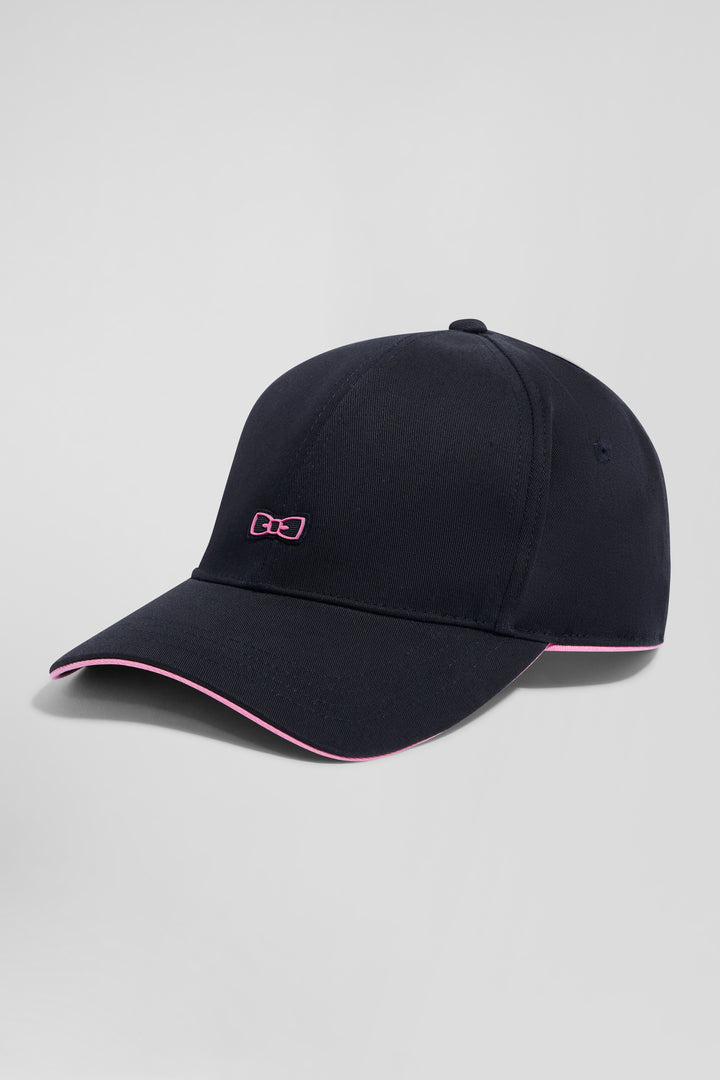 Navy blue cotton cap with bow tie badge and pink piping